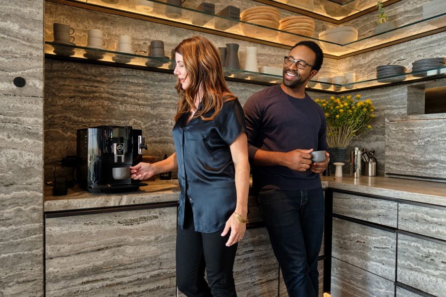 Two people drinking coffee in the kitchen. The Josh Nano is installed on the wall.