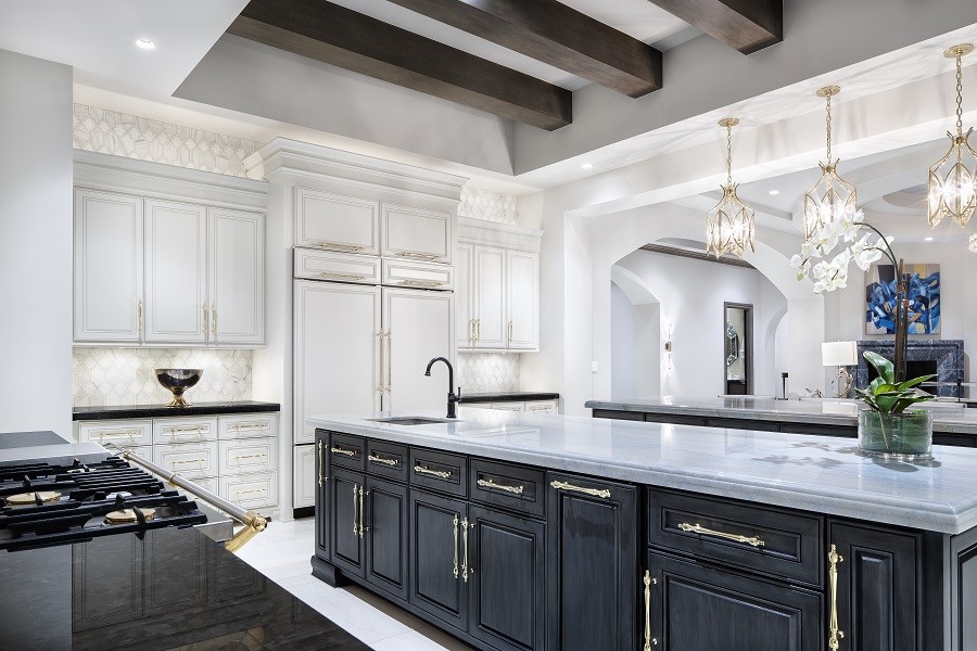 Brilliantly lit expansive kitchen accented by the deep wood cabinet, marble countertops, and bronze pulls. 