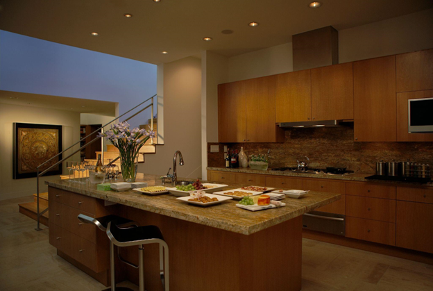 A kitchen with its island filled with appetizers is illuminated by warm, dim lighting. 