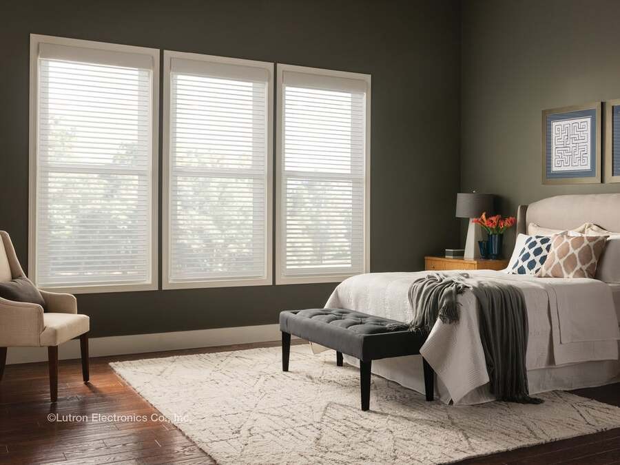 A bedroom with Lutron shades that let some sunlight come in.