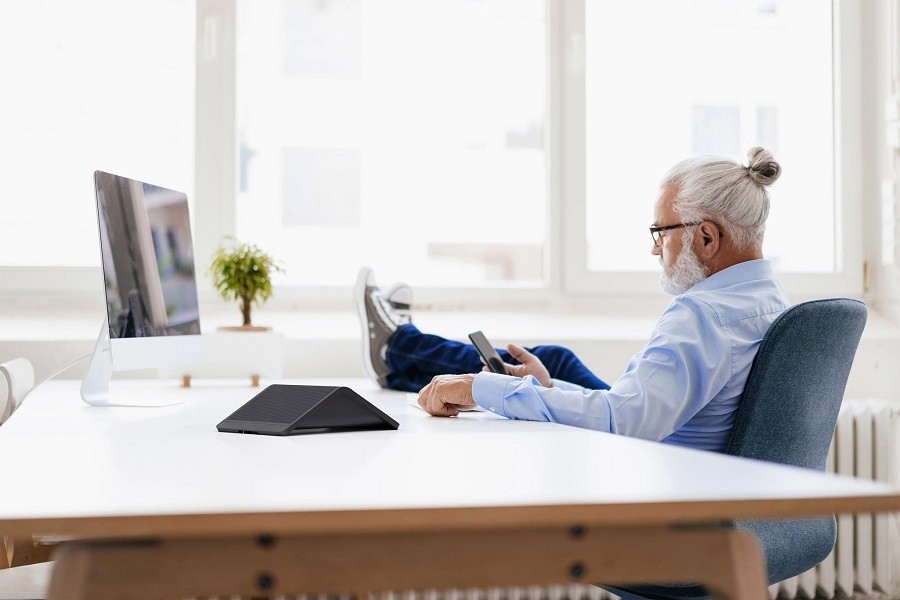 Man sits with his feet up from his home office, connecting to the office with Crestron Flex.